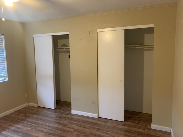 unfurnished bedroom featuring multiple closets and dark hardwood / wood-style flooring