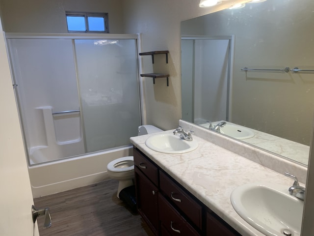 full bathroom with hardwood / wood-style flooring, vanity, combined bath / shower with glass door, and toilet