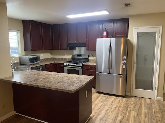 kitchen featuring light hardwood / wood-style floors, sink, stainless steel appliances, and kitchen peninsula