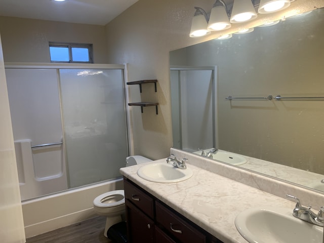 full bathroom with bath / shower combo with glass door, hardwood / wood-style floors, vanity, and toilet