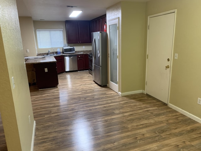 kitchen with appliances with stainless steel finishes, sink, and hardwood / wood-style floors