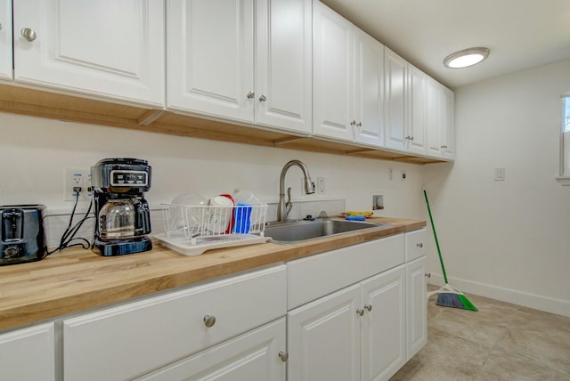 interior space featuring white cabinets, butcher block countertops, and sink