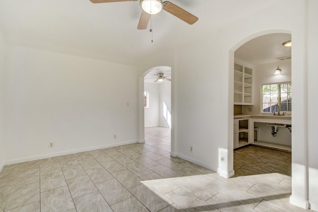 empty room with built in shelves and ceiling fan