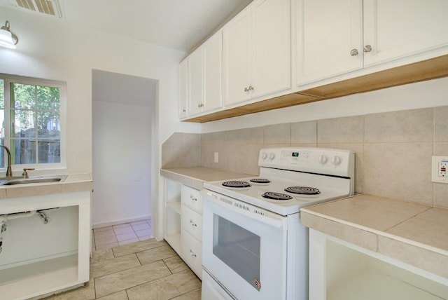 kitchen featuring sink, light tile patterned floors, tasteful backsplash, white range with electric stovetop, and white cabinetry