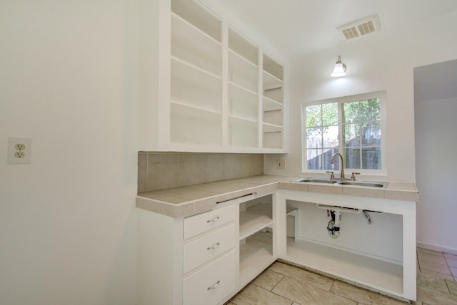 kitchen featuring white cabinetry and sink