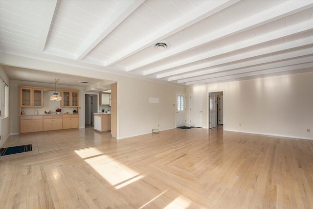 unfurnished living room featuring beamed ceiling and light hardwood / wood-style flooring