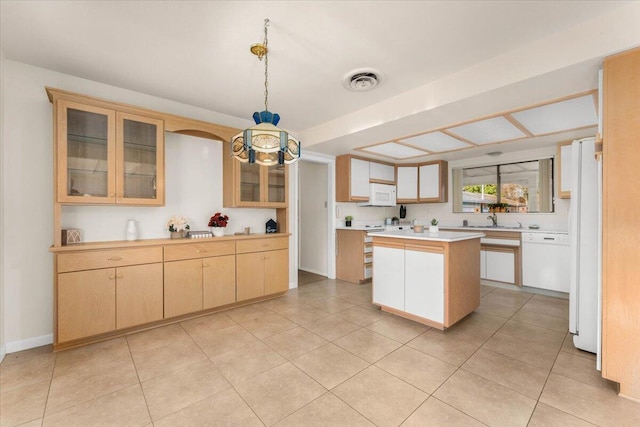 kitchen with light brown cabinetry, white appliances, sink, a center island, and hanging light fixtures