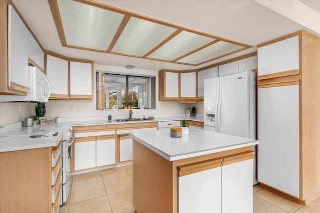 kitchen featuring white appliances, white cabinets, sink, light tile patterned floors, and a kitchen island