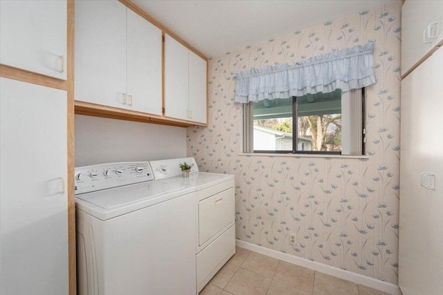 washroom with washing machine and dryer, light tile patterned floors, and cabinets