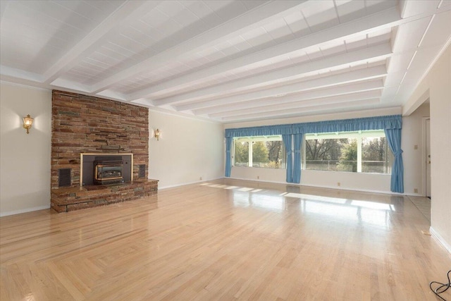 unfurnished living room featuring beamed ceiling, light wood-type flooring, and a wood stove