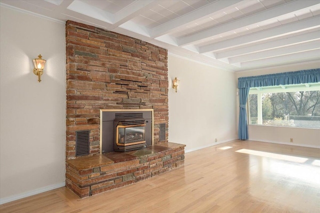 unfurnished living room featuring beamed ceiling, a wood stove, and hardwood / wood-style floors