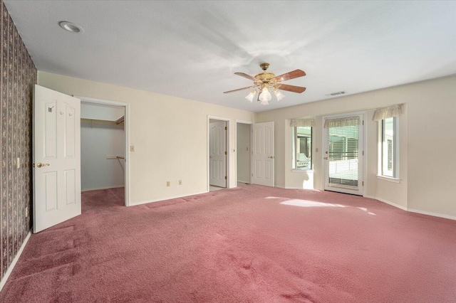 unfurnished bedroom with a walk in closet, ceiling fan, a closet, and carpet floors