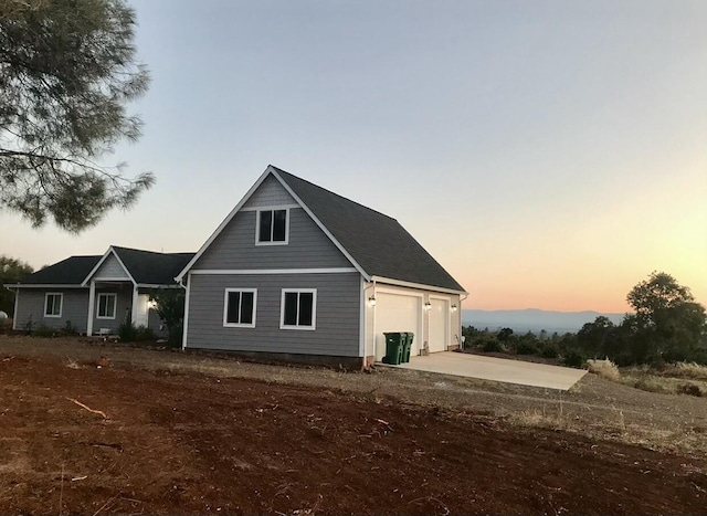 back house at dusk featuring a garage and an outdoor structure