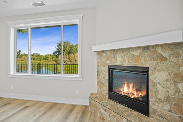 room details with a fireplace, a water view, and hardwood / wood-style flooring