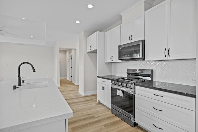 kitchen featuring light stone countertops, sink, white cabinets, and stainless steel range with gas stovetop