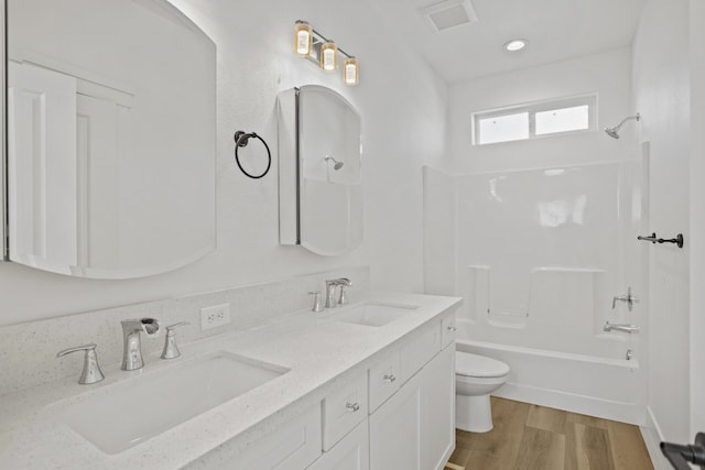 full bathroom featuring washtub / shower combination, hardwood / wood-style floors, vanity, and toilet