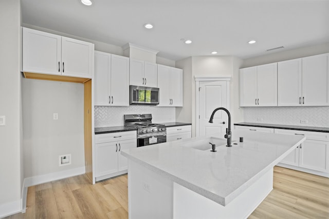 kitchen featuring white cabinets, appliances with stainless steel finishes, sink, and an island with sink