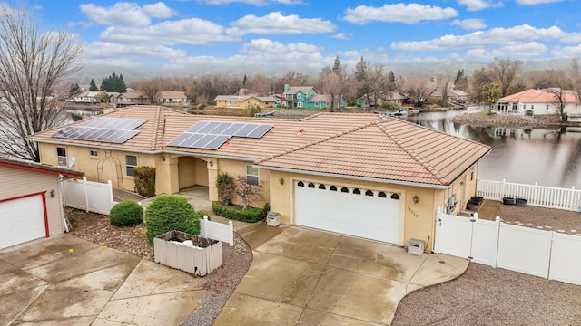 view of front of property featuring solar panels, a garage, and a water view