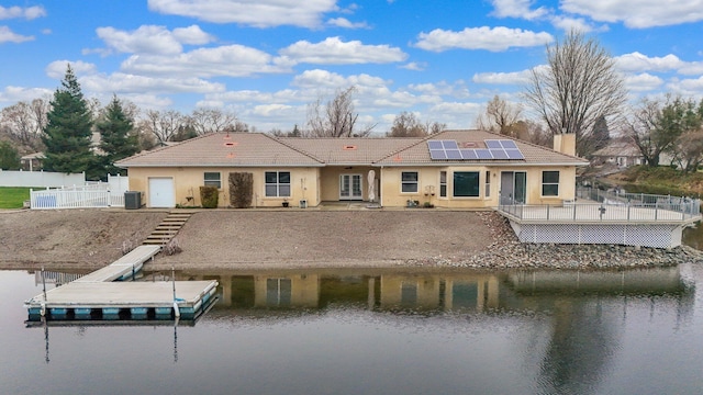 back of house with a water view and solar panels