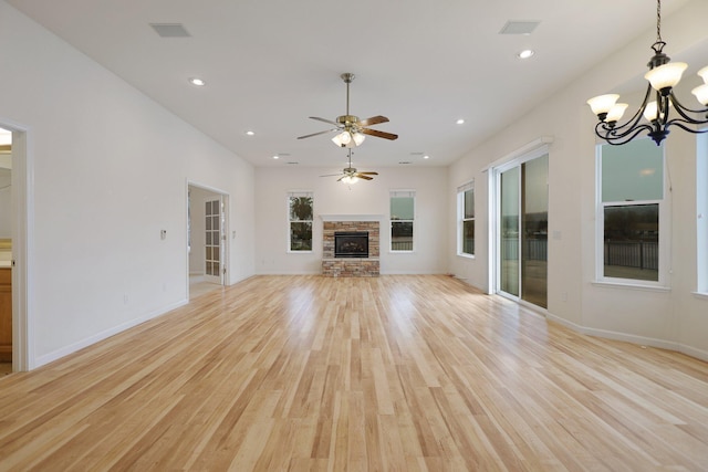 unfurnished living room featuring a fireplace, light hardwood / wood-style floors, and ceiling fan with notable chandelier