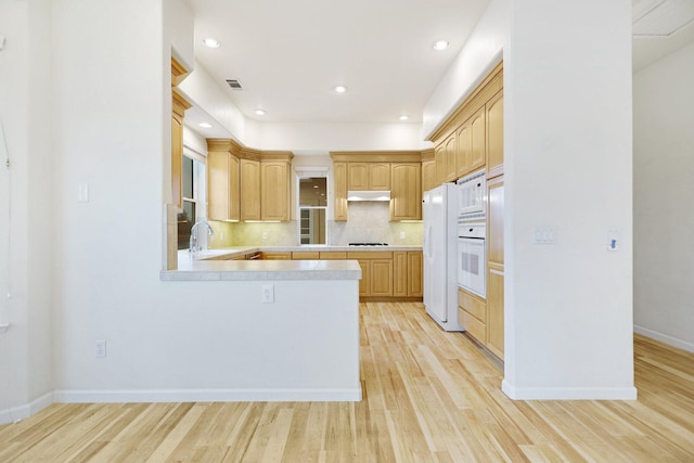 kitchen featuring sink, light hardwood / wood-style flooring, backsplash, white appliances, and light brown cabinetry