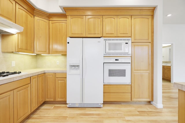 kitchen with light brown cabinets, light wood-type flooring, white appliances, and ventilation hood