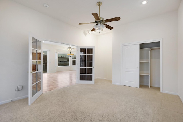 unfurnished bedroom with a closet, ceiling fan, french doors, and light colored carpet