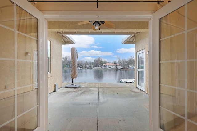 view of patio with a water view and ceiling fan