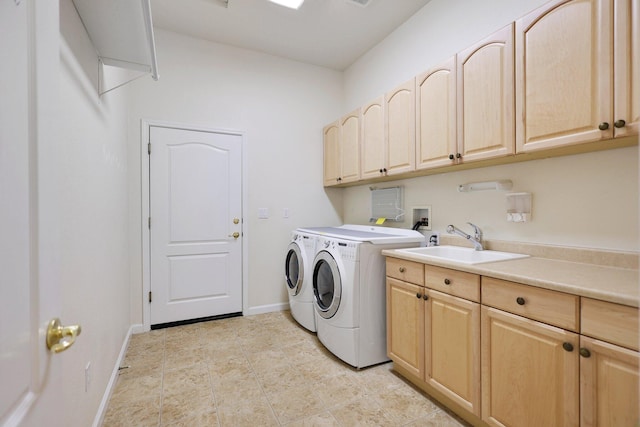 clothes washing area with cabinets, washing machine and dryer, and sink