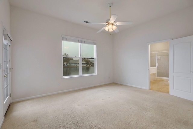 unfurnished bedroom with light carpet, connected bathroom, and ceiling fan