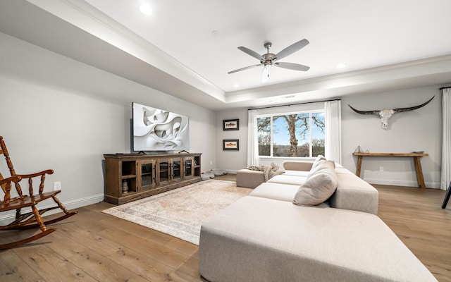 living room featuring hardwood / wood-style floors, a raised ceiling, ceiling fan, and crown molding