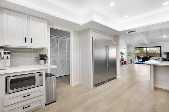 kitchen featuring tasteful backsplash, white cabinetry, light hardwood / wood-style flooring, and stainless steel appliances