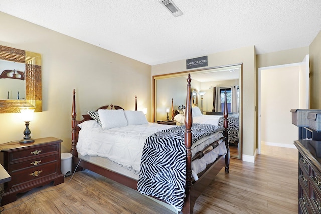 bedroom featuring a textured ceiling, light hardwood / wood-style flooring, and a closet