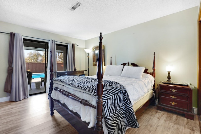 bedroom featuring light wood-type flooring, a textured ceiling, and access to outside