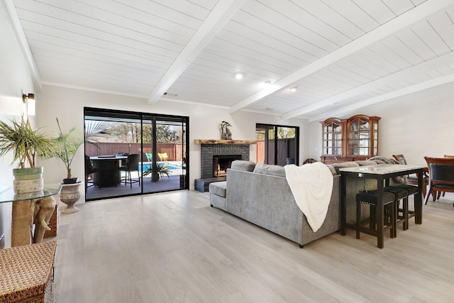 living room featuring beam ceiling, light hardwood / wood-style floors, a brick fireplace, and wooden ceiling