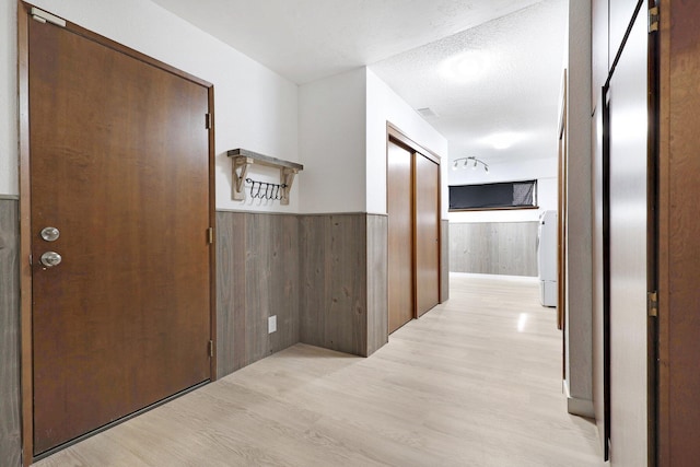 hallway featuring light hardwood / wood-style floors, a textured ceiling, and washer / clothes dryer