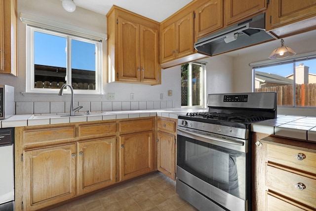 kitchen with sink, tile countertops, dishwashing machine, and gas stove