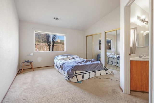 bedroom with ensuite bath, lofted ceiling, and carpet flooring