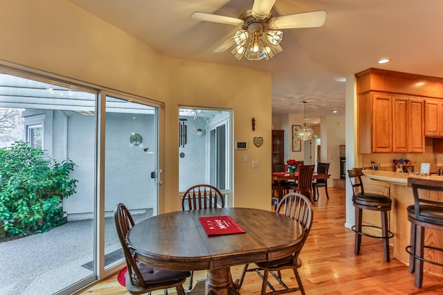 dining space with light hardwood / wood-style flooring and ceiling fan with notable chandelier