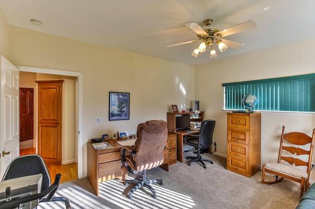 carpeted office space featuring ceiling fan