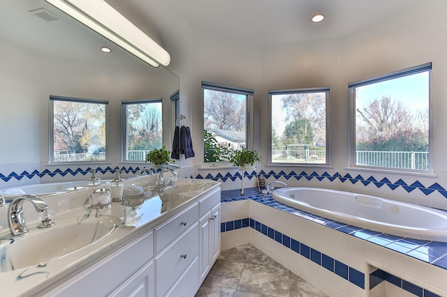 bathroom with tile patterned flooring, vanity, and tiled bath