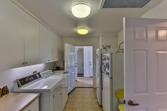 clothes washing area with separate washer and dryer, light tile patterned flooring, and cabinets