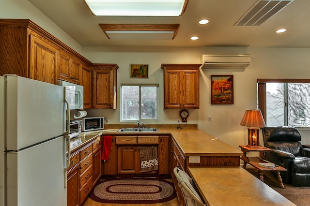 kitchen featuring white appliances, sink, and a wall unit AC