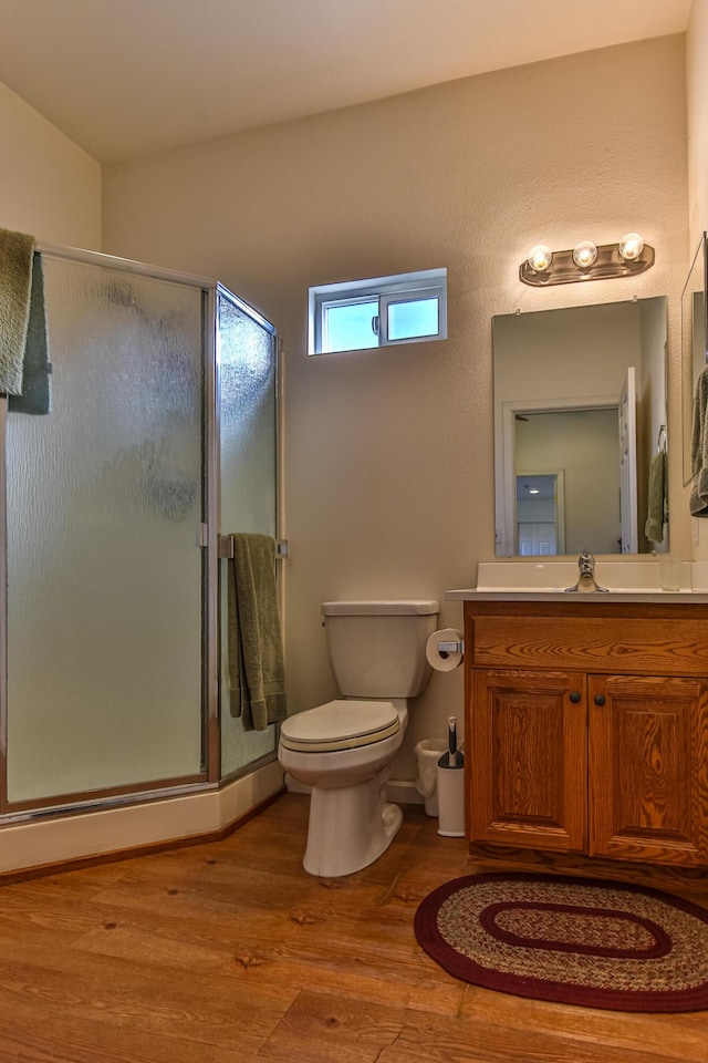 bathroom with hardwood / wood-style flooring, vanity, toilet, and an enclosed shower