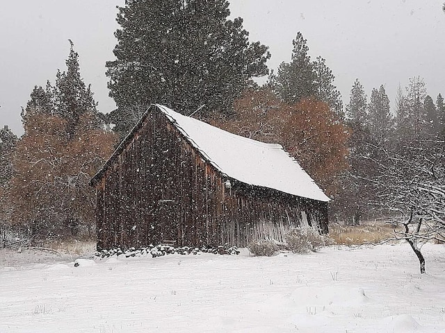 view of snowy exterior featuring an outbuilding