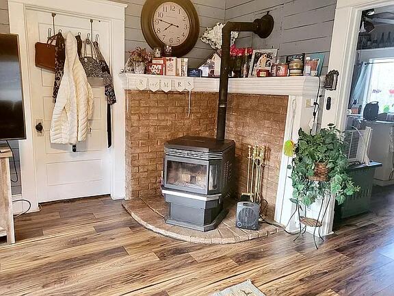 interior details with hardwood / wood-style flooring, a wood stove, and wooden walls