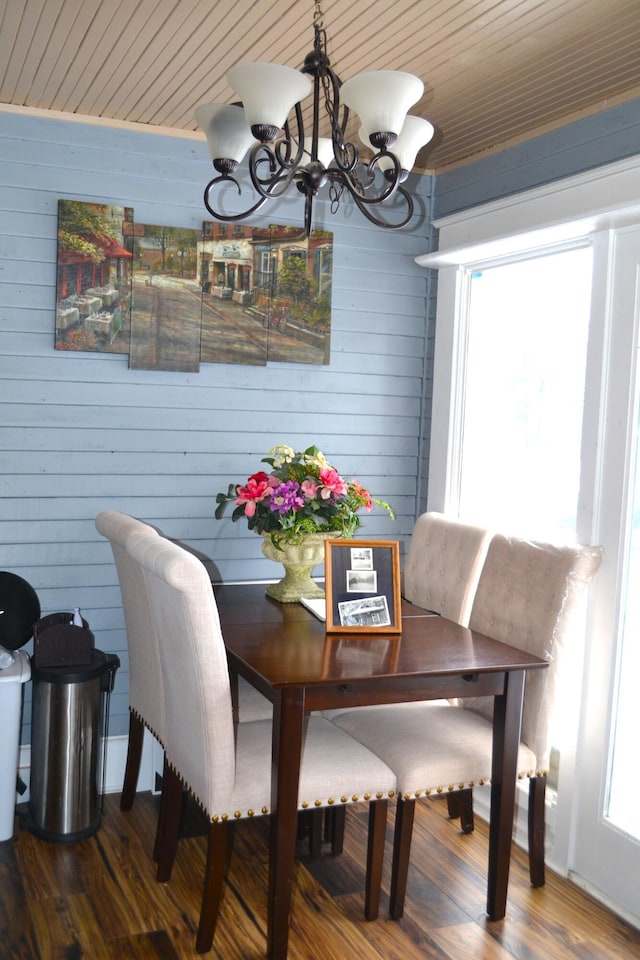 dining room with a notable chandelier, wood walls, and wood-type flooring