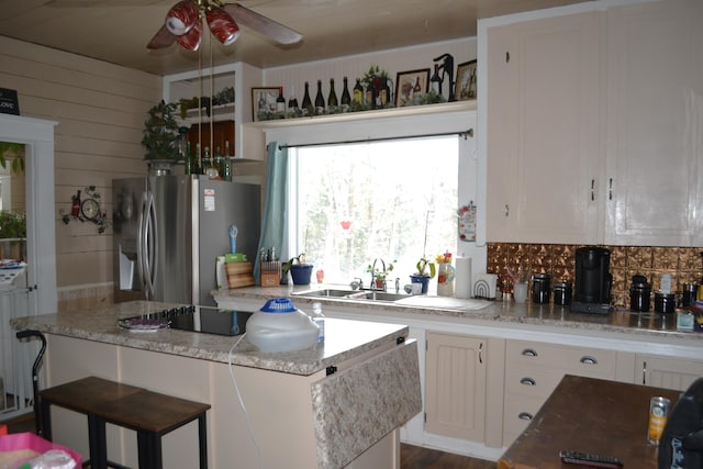 kitchen featuring white cabinets, sink, ceiling fan, stainless steel fridge, and light stone counters