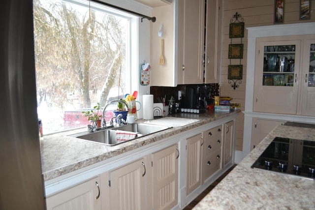 kitchen with tasteful backsplash, black electric cooktop, white cabinetry, and sink