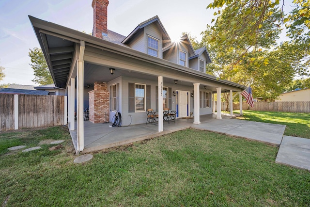 rear view of property featuring a lawn and a patio